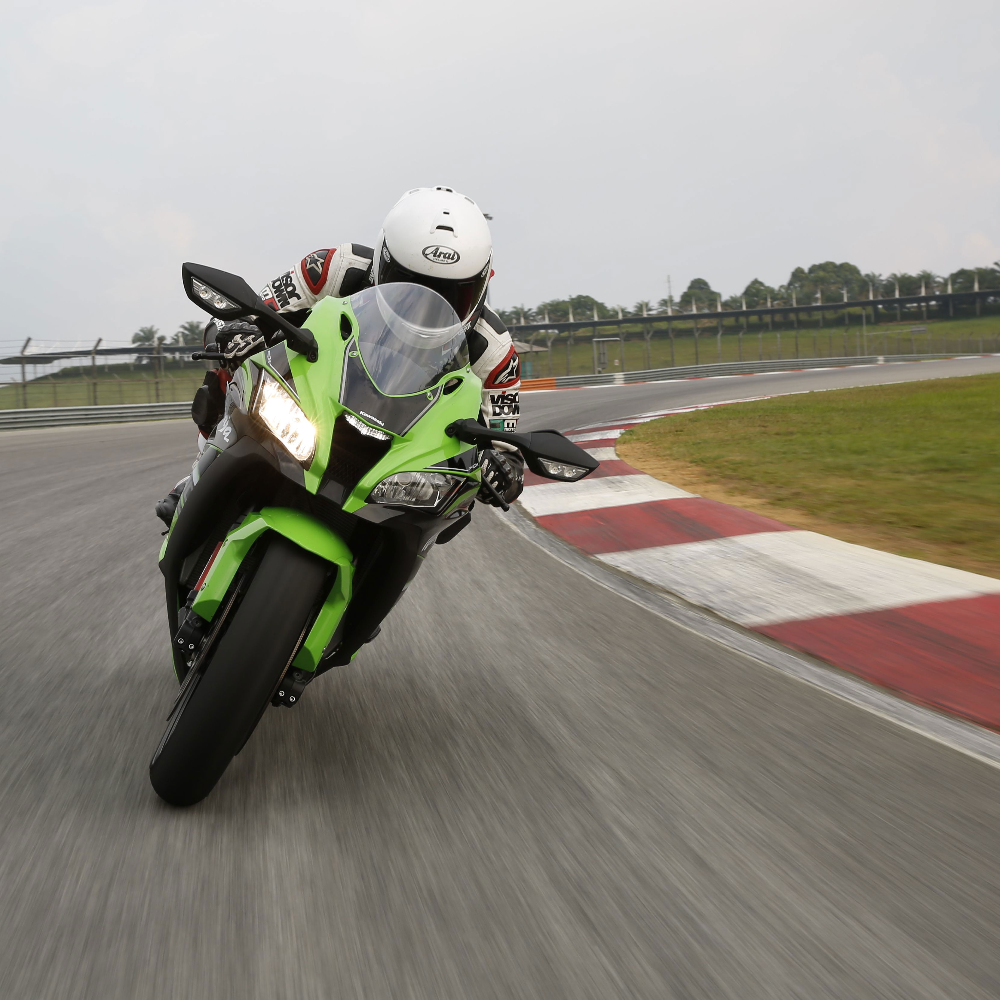 A front-on picture of a green and black 2016 Kawasaki ZX-10R being ridden on a track